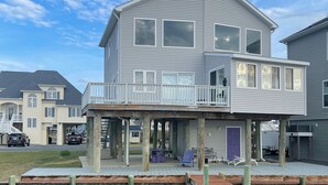 Une maison à deux étages située au bord de l’eau, dotée d’une terrasse couverte, d’un quai et d’un espace d’amarrage pour bateaux.