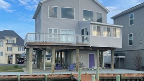 Une maison à deux étages située au bord de l’eau, dotée d’une terrasse couverte et d’un quai s’avançant dans l’eau.