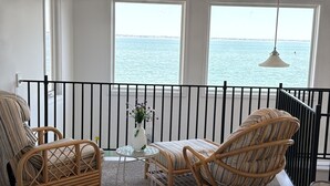 Un balcon avec des fauteuils en osier, une petite table et un vase rempli de fleurs.