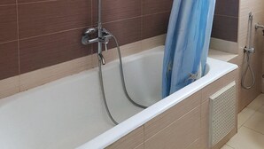 Ein Badezimmer mit einer Badewanne, einer Dusche und einem Handtuchhalter.