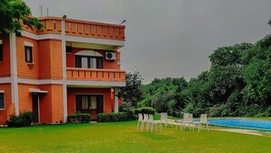 A multi-story building with a flat roof and a large lawn in front. - Hills Nature Resort (Gurugram)