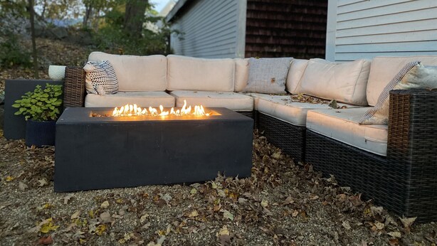 An outdoor seating area with a fire feature, a sofa, and a side table. - Meredith Charmer-walk to lake, town, shops, & boat launch (Meredith)