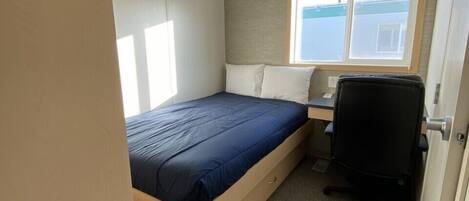 A compact room with a bed, a desk, and a chair.