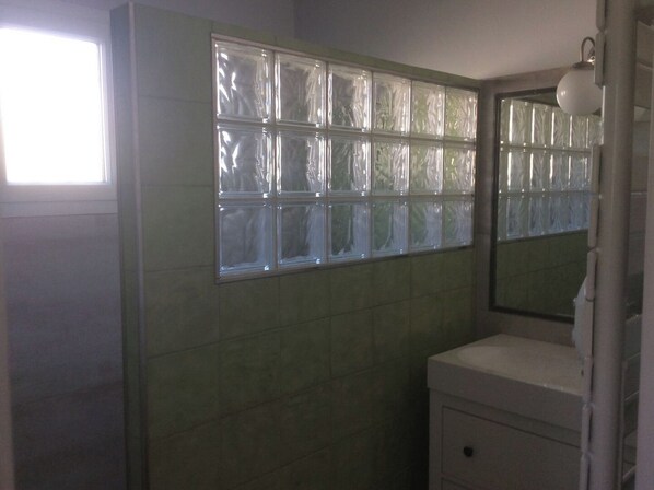 A bathroom with a tiled wall, a window with frosted glass, and a white sink.
