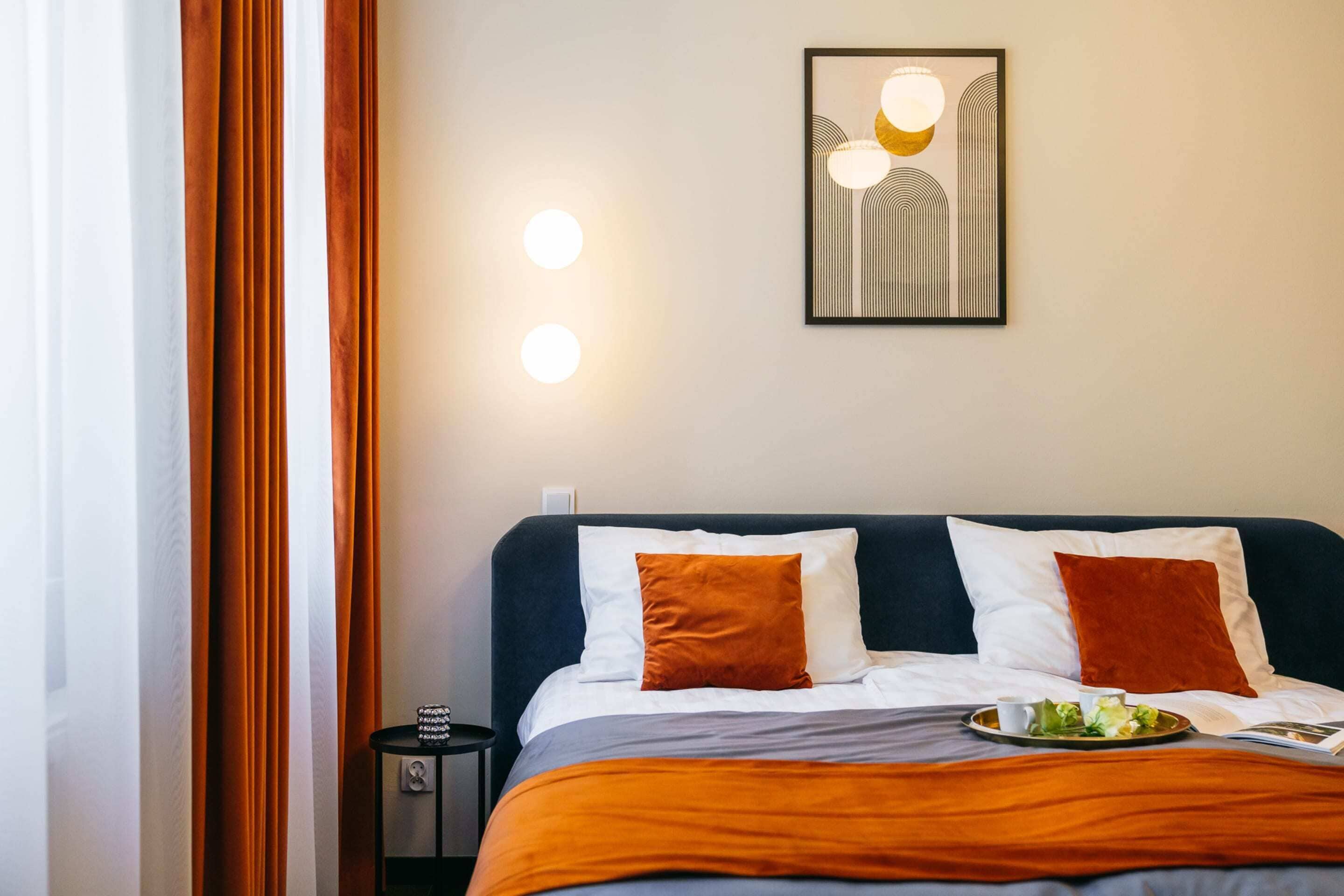 Una cama bien hecha con un cabecero oscuro, dos almohadas y una manta. Encima de la cama, hay un cuadro en la pared.