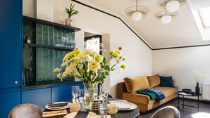 A modern dining area with a round table set for four, a sofa, and a coffee table. - Estery12 (Kraków)