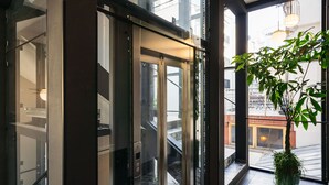 A modern elevator with glass doors and a potted plant beside it. - Estery12 (Kraków)