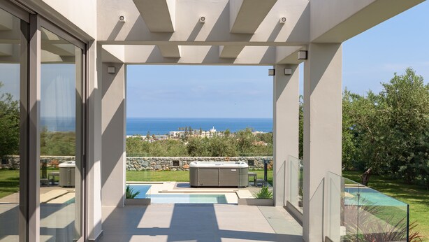 Un patio moderno al aire libre con jacuzzi, piscina y vista al mar.