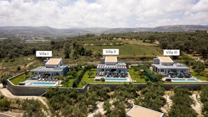 Tres villas con piscinas, rodeadas de vegetación y colinas.