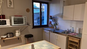 A compact kitchen with a microwave, toaster, coffee maker, and a small dining table. - Meublé de tourisme in an old farmhouse for 4 people ( 2 stars) (Anould)