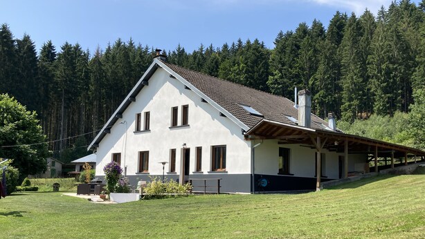 A two-story house with a sloped roof, a covered porch, and a well-maintained lawn. - Meublé de tourisme in an old farmhouse for 4 people ( 2 stars) (Anould)