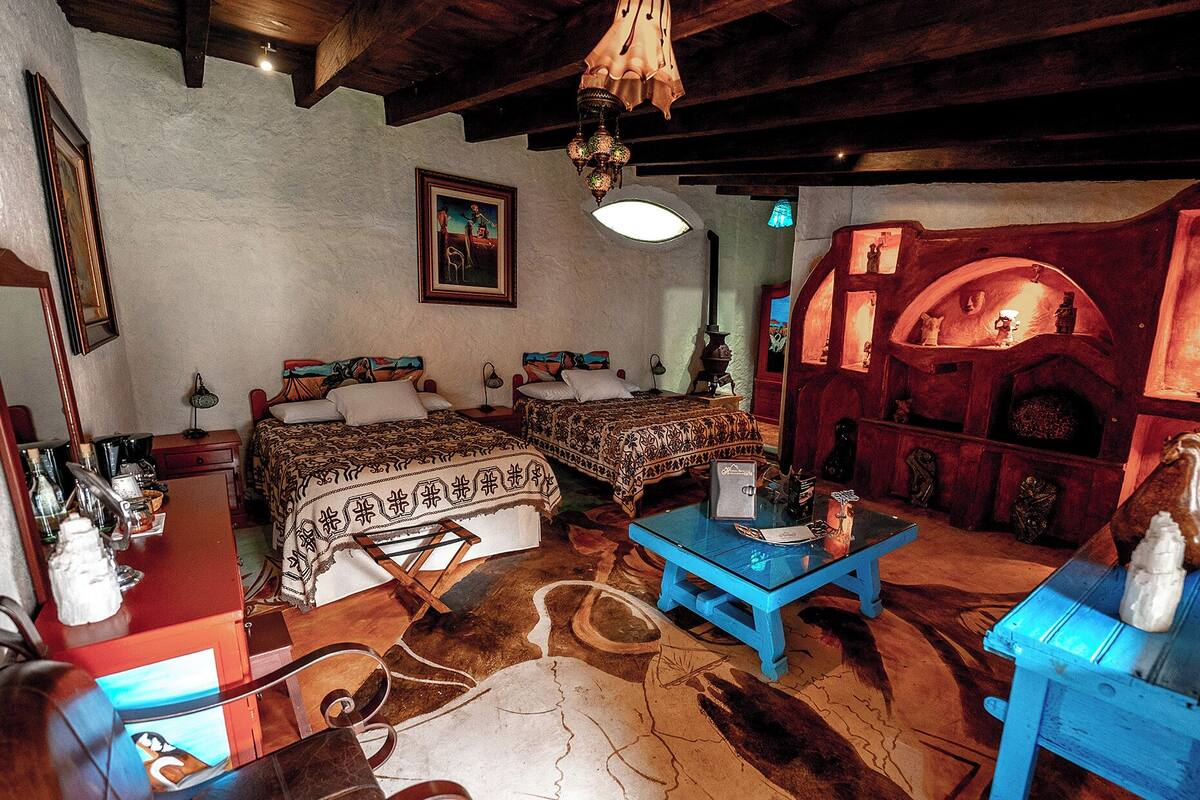 Ein traditionell eingerichtetes Zimmer mit zwei Betten, einer Holzbalkendecke und einer roten Wand mit Regalen.