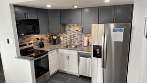 Una cocina moderna con gabinetes grises, electrodomésticos de acero inoxidable, horno empotrado y lavavajillas.