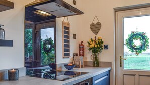 A kitchen with an island, a fire extinguisher, a weekly menu board, a vase with flowers, and a door with a wreath. - 2 bedroom accommodation in Cluny, near Kirkcaldy (Cluny, near Kirkcaldy)