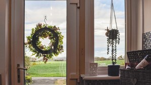 A door with a wreath and a hanging plant, a window with a view of greenery, and a basket with items on the windowsill. - 2 bedroom accommodation in Cluny, near Kirkcaldy (Cluny, near Kirkcaldy)