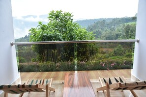 Ein Balkon mit Holzboden, zwei Holzstühlen und einem Glasgeländer.