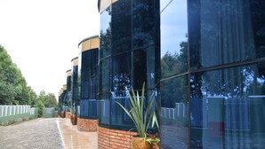 A modern building with reflective glass windows and brick accents. - Chimpanzee Lodge (Bushekeri)