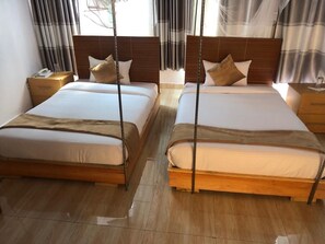 Ein Hotelzimmer mit zwei Betten, Holz-Kopfteilen und einem Nachttisch mit Telefon.