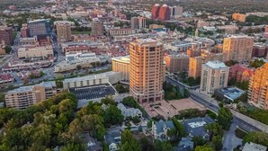 Vista aérea de un paisaje urbano con diversos edificios, calles y áreas verdes.