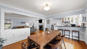 Una cocina amplia con armarios blancos, una mesa de comedor de madera y una barra.