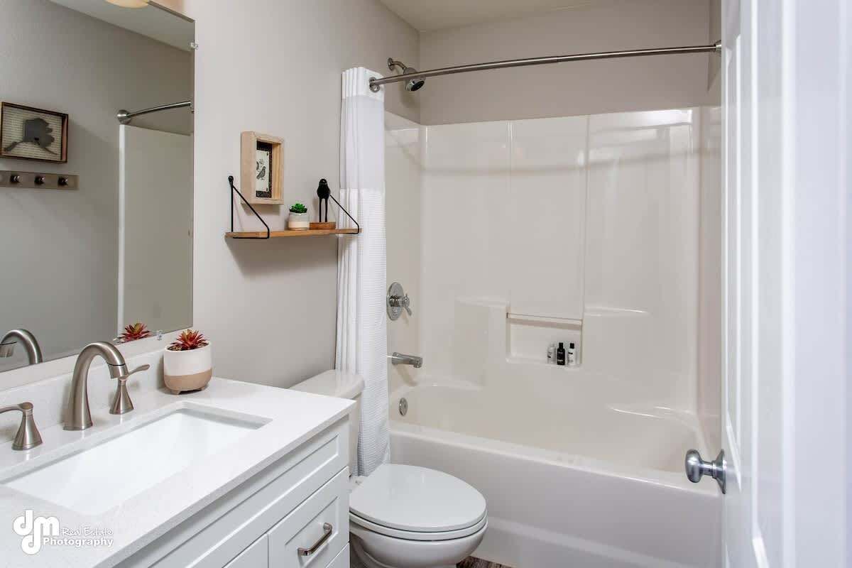 Un baño moderno con lavamanos blanco, inodoro y ducha con mampara de vidrio.