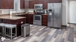 Una cocina moderna con armarios de madera oscura, electrodomésticos de acero inoxidable y una isla central con taburetes de bar.