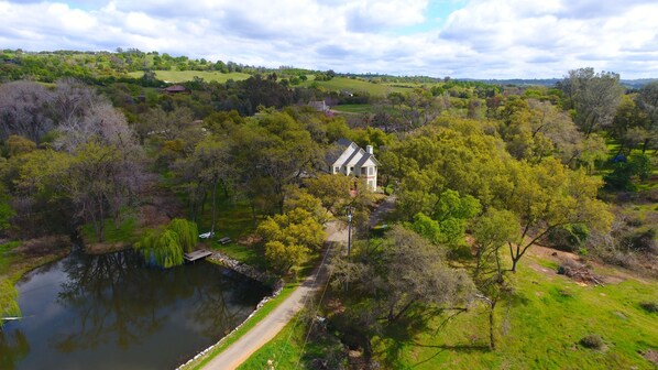 A house surrounded by lush greenery and a pond.