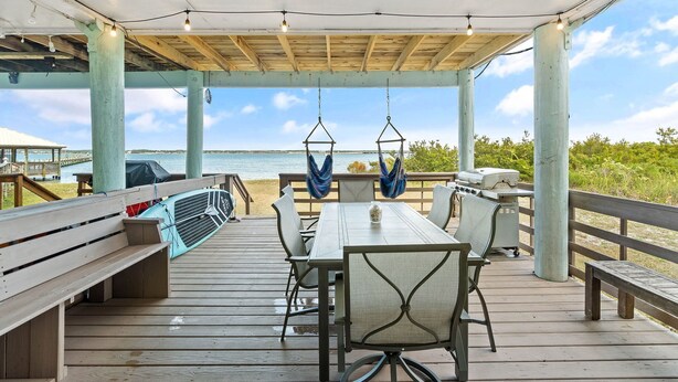 A covered outdoor deck with a table and chairs, a grill, and hammocks.