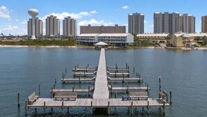 A waterfront hotel with a long pier extending into the water, surrounded by high-rise buildings.