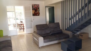 Un salon avec un canapé, une table à manger et des chaises, ainsi qu’un escalier.