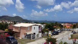 Un quartier résidentiel avec des maisons, une clôture blanche et une vue sur la mer et les montagnes.