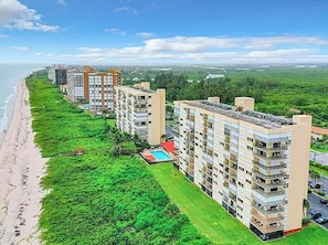 Um edifício residencial alto com várias varandas, piscina e vista para a praia.
