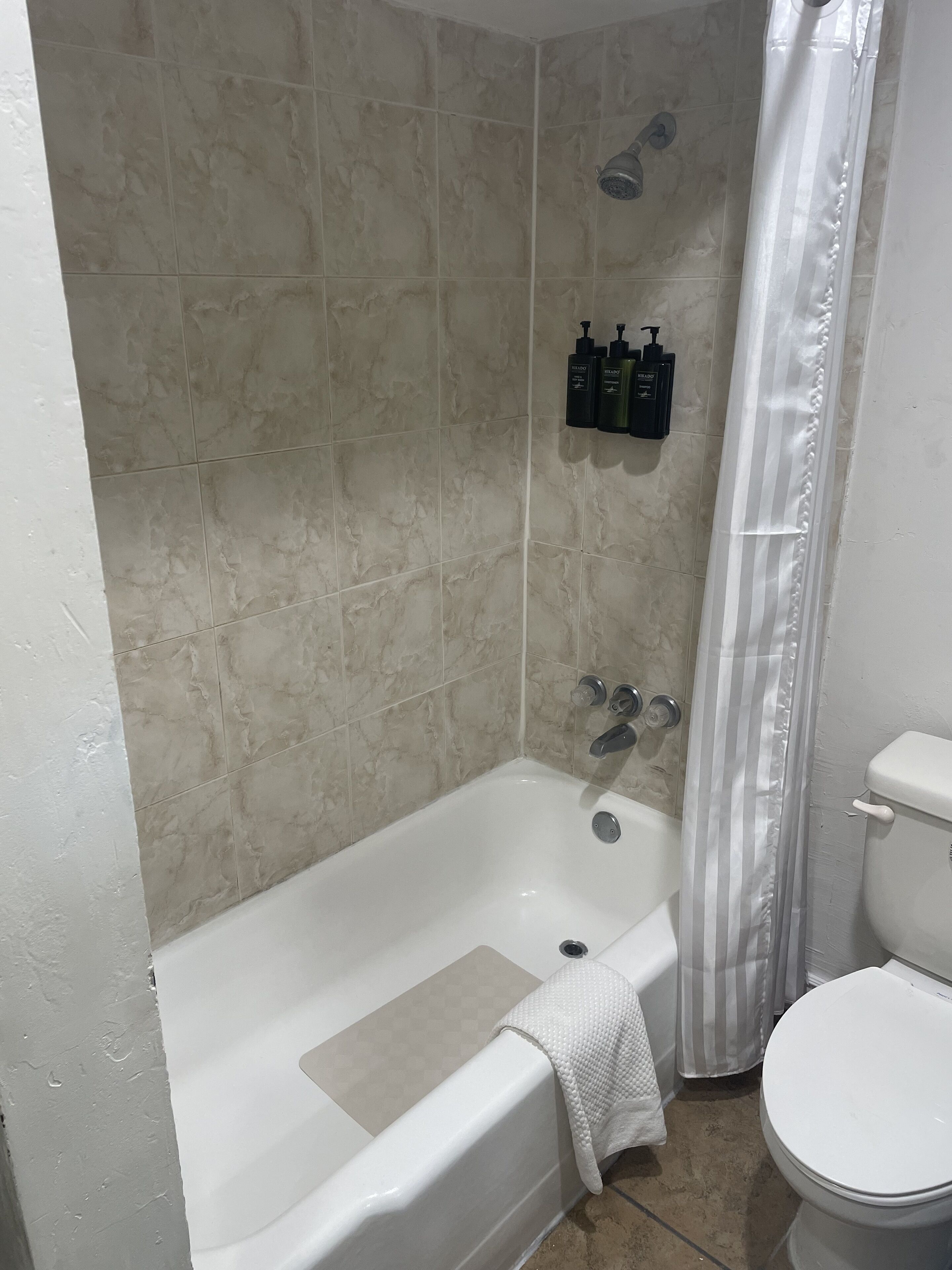 A bathroom with a bathtub, shower, and toilet.