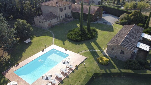 Vue aérienne d’une propriété dotée d’une piscine, d’un court de tennis et d’un jardin aménagé.