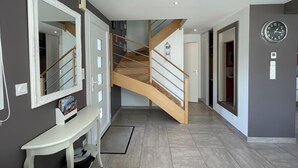 En modern inredning med en trappa, en bänk, en spegel och en klocka på väggen.