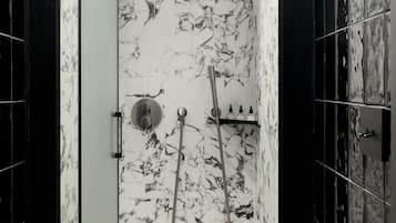 Un baño con pared de mármol, ducha y lavabo.