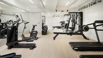 Ein modernes Fitnessstudio mit unterschiedlichen Trainingsgeräten, darunter Laufbänder und Kraftgeräte, sowie einem großen Spiegel an einer Wand.
