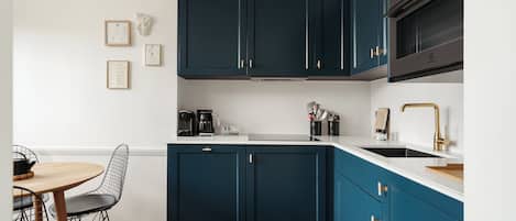 A modern kitchen with dark blue cabinets, a white countertop, and a black and white patterned floor.