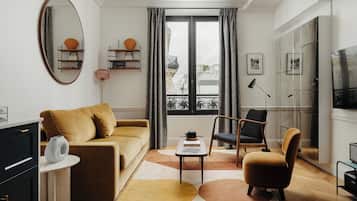 A modern living room with a sofa, armchair, coffee table, and a large mirror.
