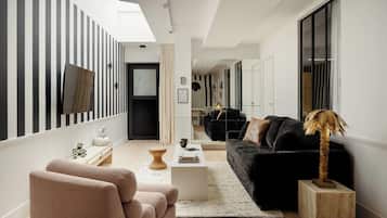 Un salon moderne avec un canapé noir, une table basse en bois et une sculpture originale représentant un palmier.