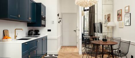 A modern kitchen with dark blue cabinets, a white countertop, and a black and white patterned rug.