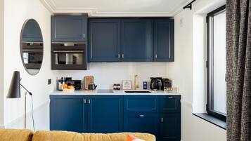 A compact kitchen with dark blue cabinets, a white countertop, and a modern stove.
