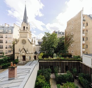 A historic church with a tall spire and a courtyard with lush greenery.