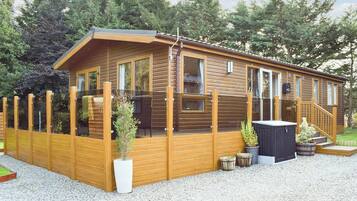 A wooden cabin with a covered porch, large windows, and a small outdoor seating area.