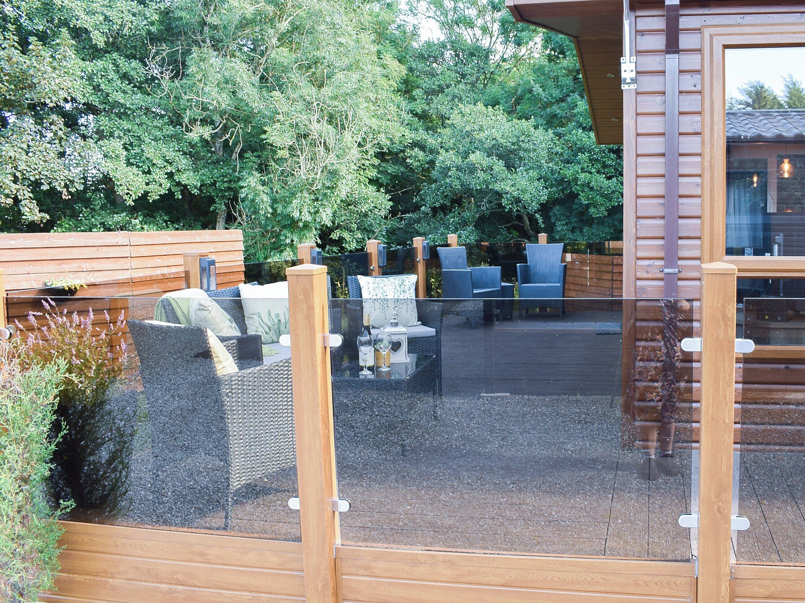 An outdoor seating area with wicker furniture and a glass partition.