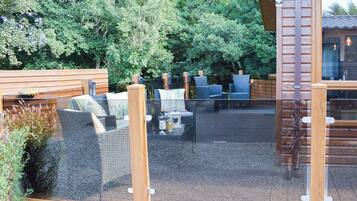 An outdoor seating area with wicker furniture and a glass partition.