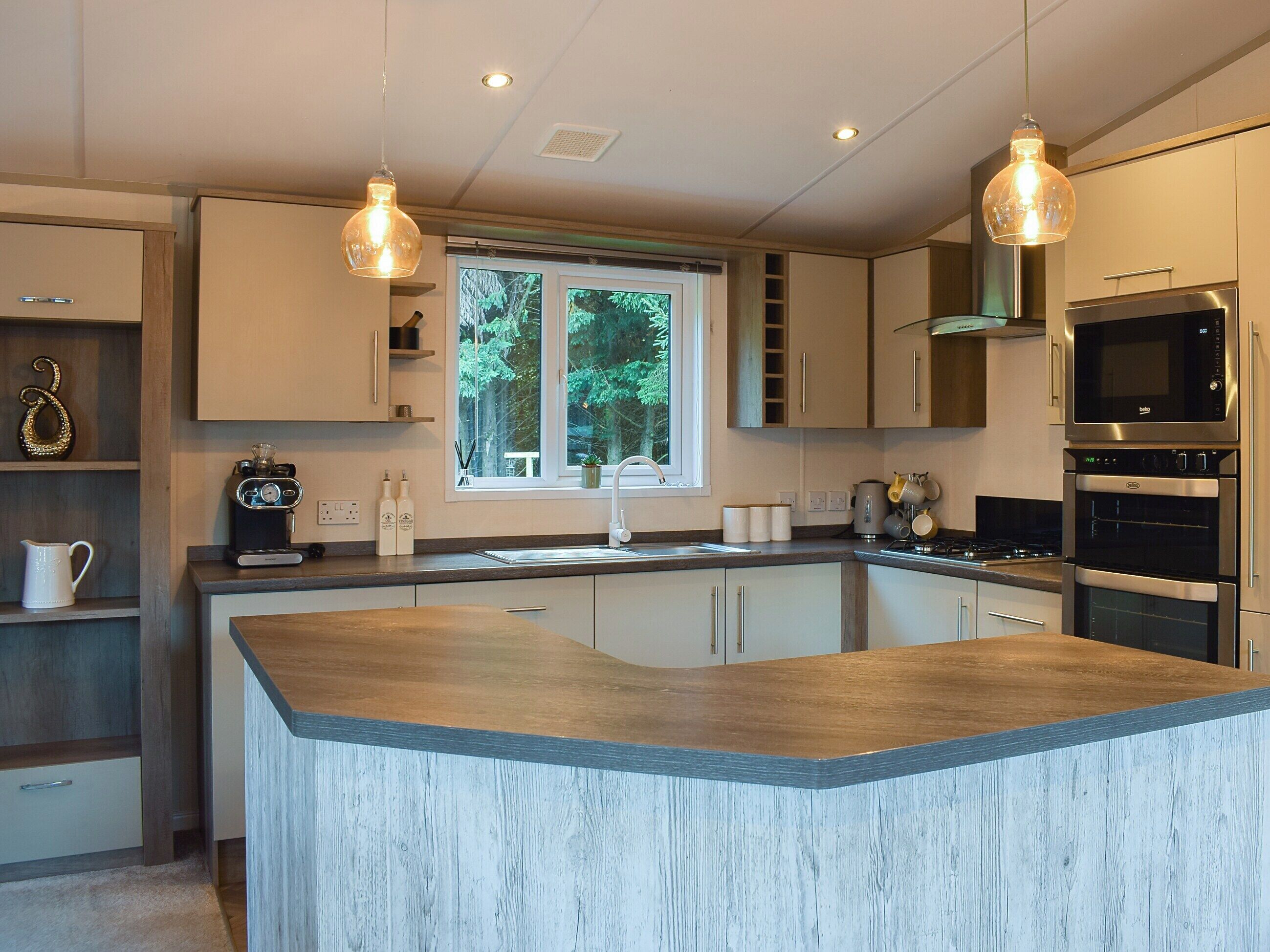 A modern kitchen with a central island, stainless steel appliances, and pendant lighting.