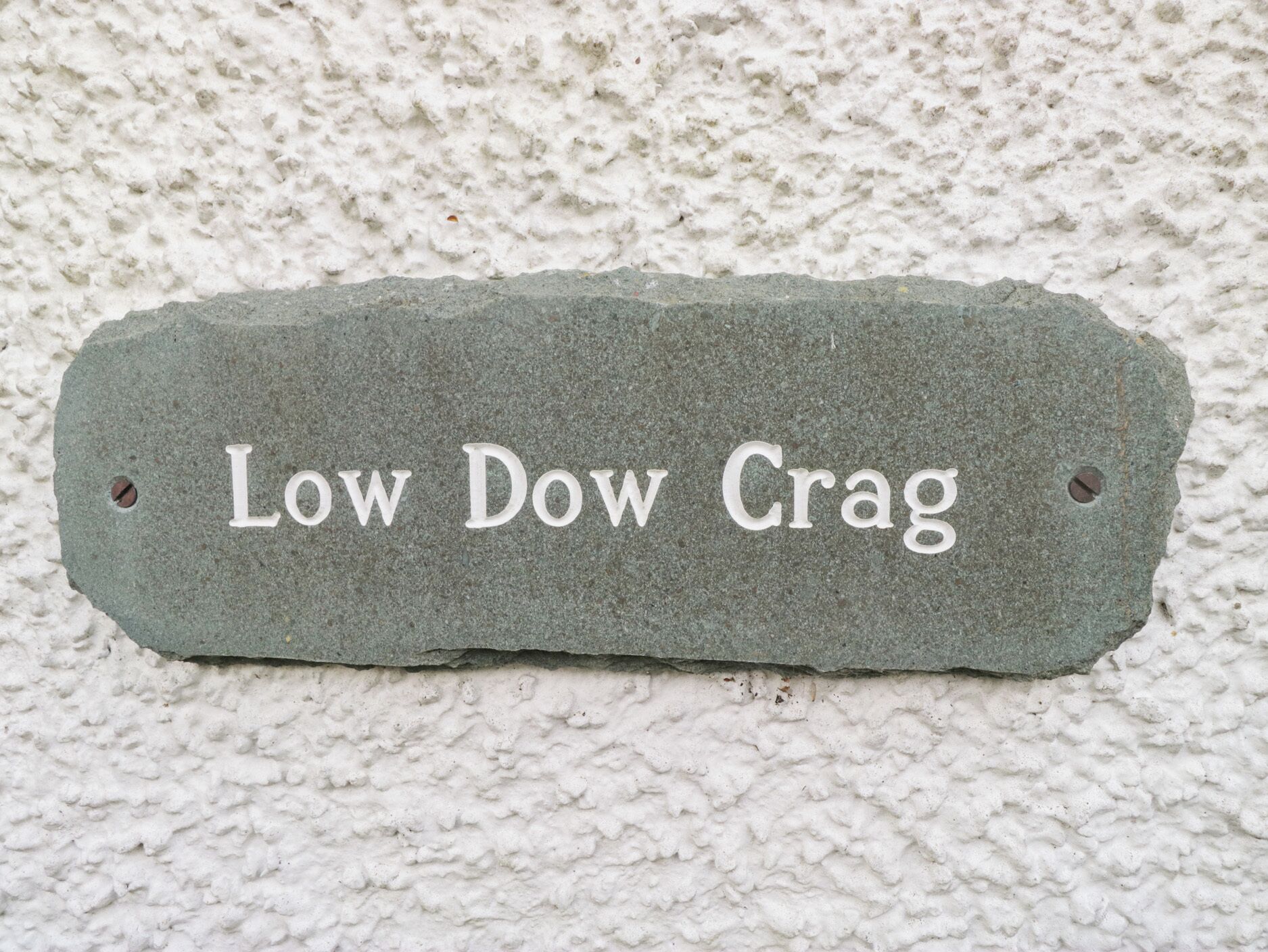 A stone plaque with the inscription "Low Dow Crag" against a textured wall.