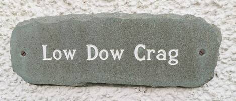 A stone plaque with the inscription "Low Dow Crag" against a textured wall.