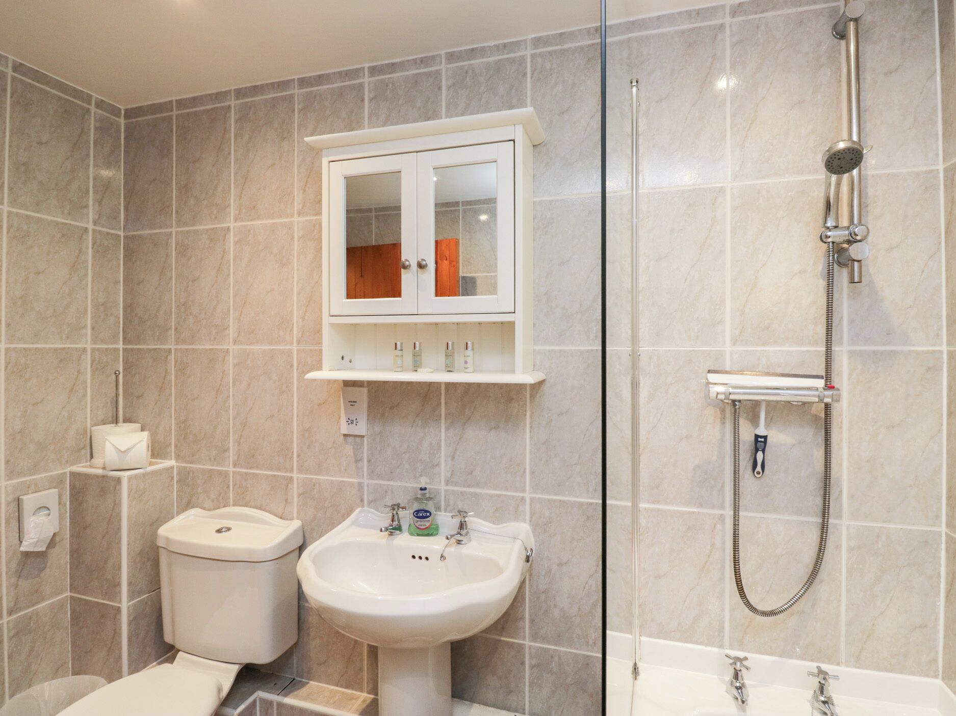 Et moderne badeværelse med toilet, vask og brusebad.